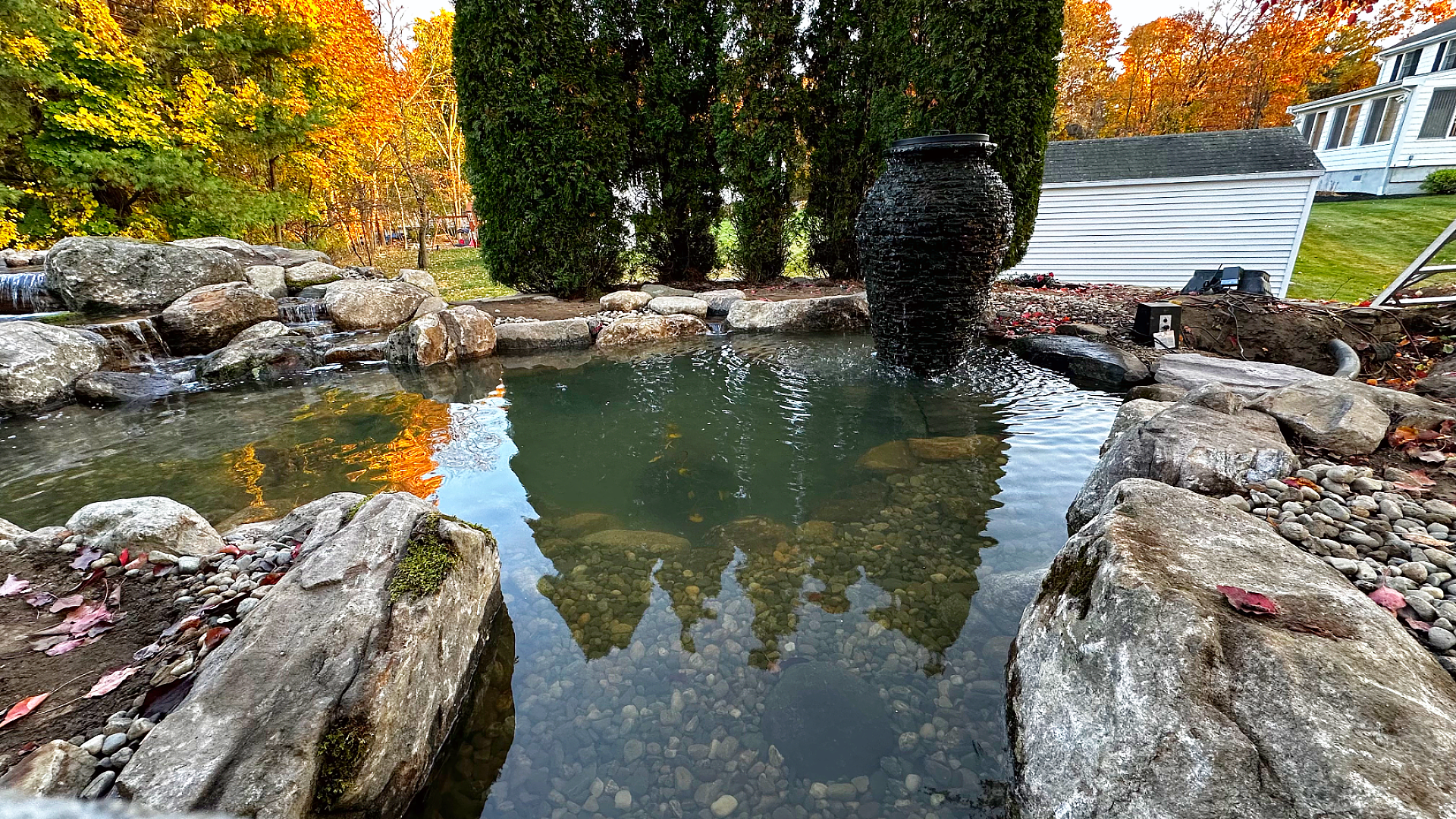 Tranquil garden pond with autumn foliage reflection.