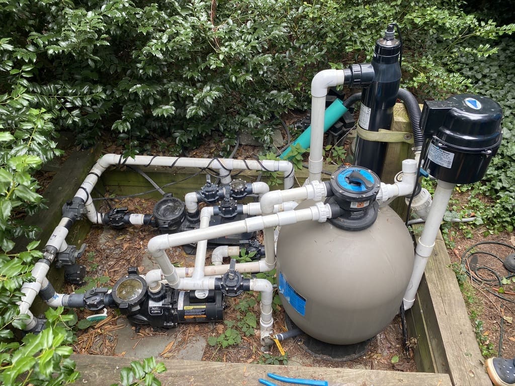 Swimming pool pump system in garden setting.