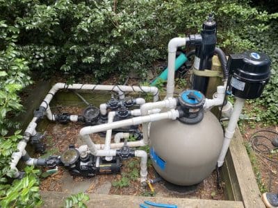 Swimming pool pump system in garden setting.